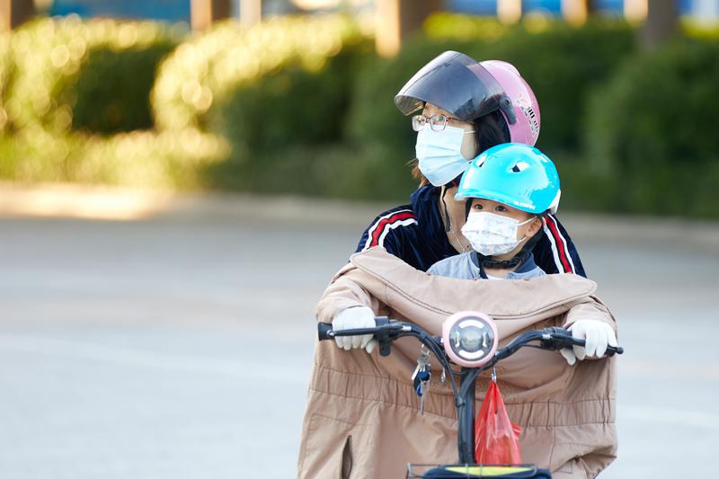 一位母亲用外套为孩子挡风。佛山日报记者吕润致摄