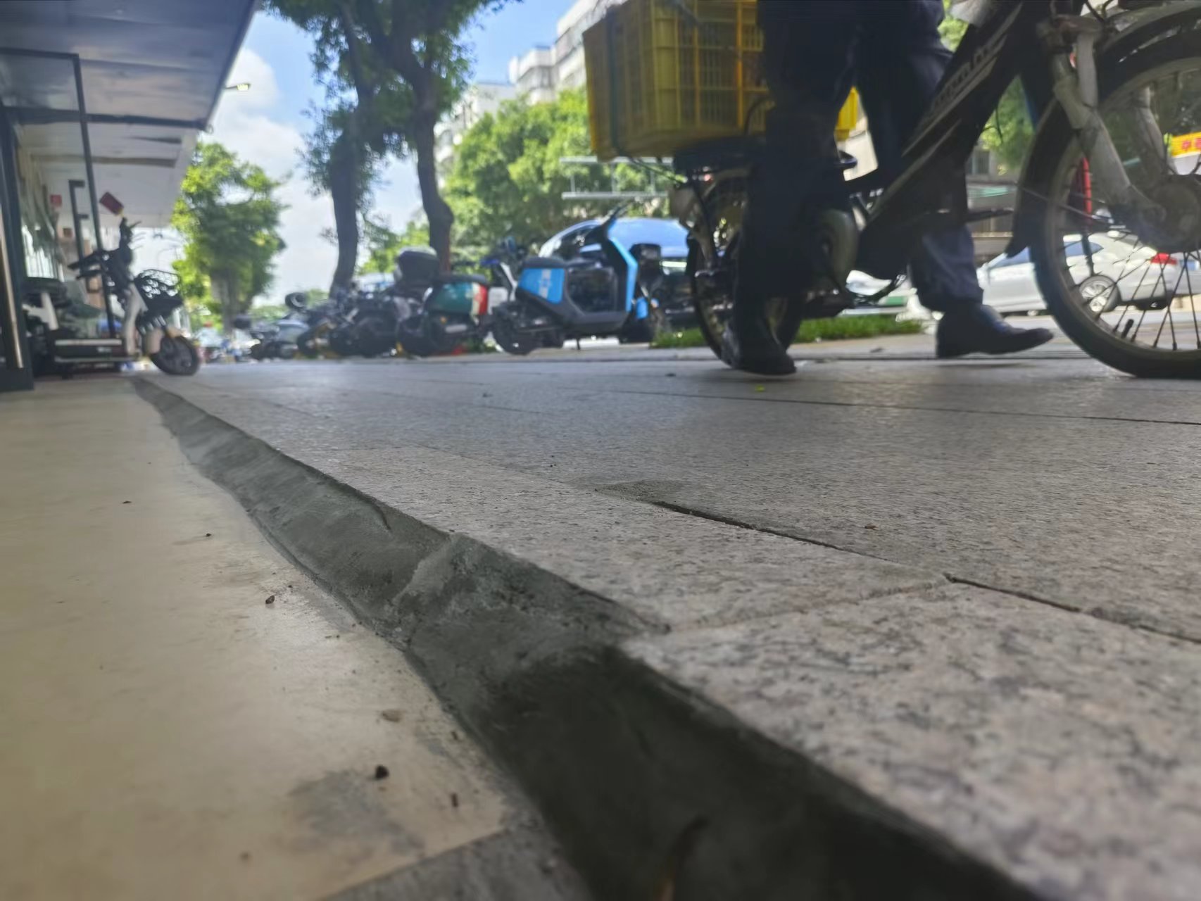 针对路基比店铺地面高的情况,施工人员把店铺和路基交界处的人行道砖抬高,形成一个反向横坡,解决雨水倒灌问题。佛山市新闻传媒中心记者吕嘉怡摄.jpg
