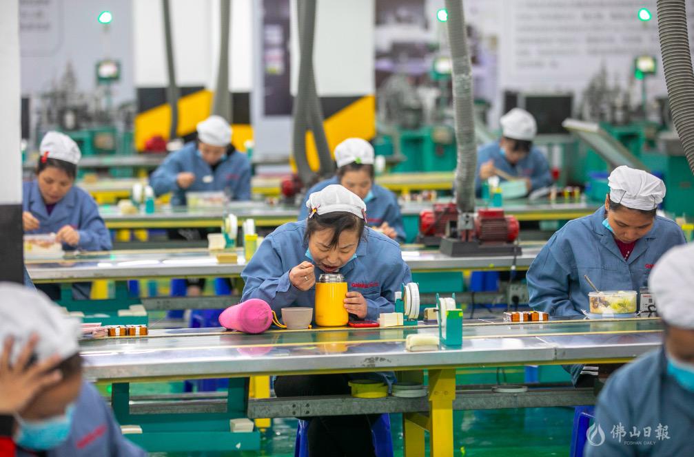 为避免人员聚集,广东格兰仕取消员工饭堂聚餐,以班组为单位打包盒饭。图为近日,复工员工正在各自工位上吃饭,每人间隔在1米以上。/佛山日报记者龙翔摄