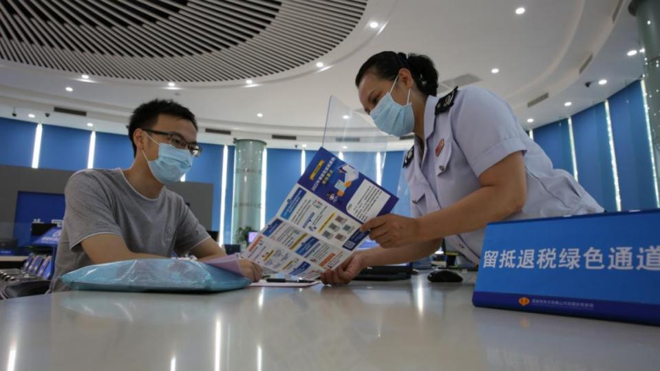 高明区税务局第一税务分局税务干部向纳税人讲解留抵退税扩围政策。通讯员供图.png