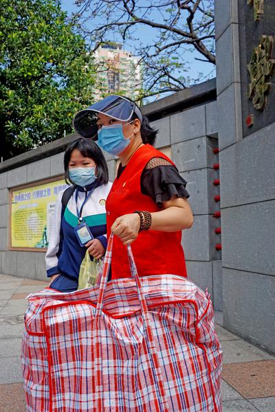 佛山三中初中部校门口,家长帮助学生搬送书籍行李。/佛山日报记者谭兼之摄