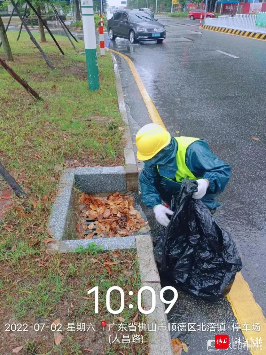 工作人员沿街清除排水口落叶.jpg