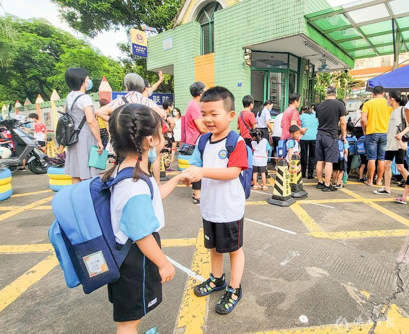 2021年9月1日,开学首日,顺德区乐从镇的经华幼儿园,第一天入幼儿园小班的周泽慈在门口遇到邻居妹妹,他们相互握手打招呼。佛山日报记者周春摄
