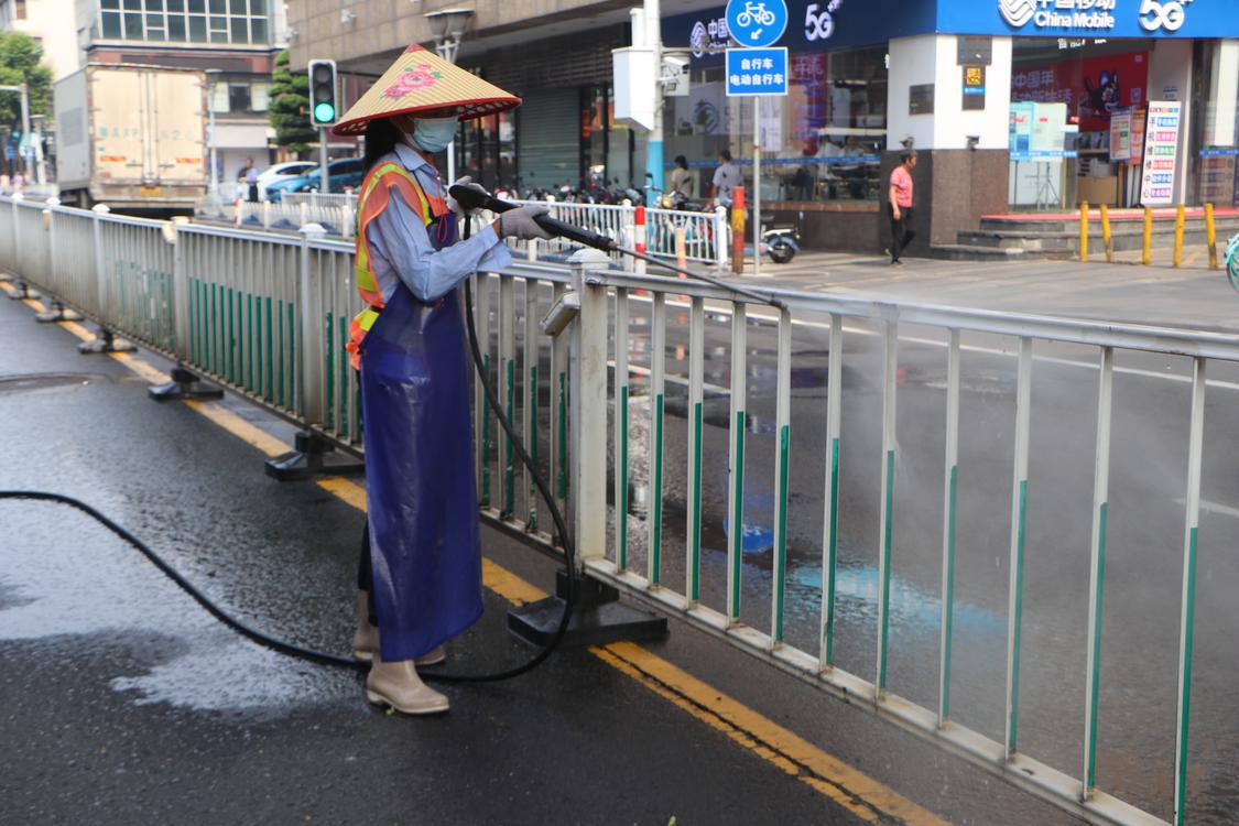 环卫工人使用水枪清洗护栏。.jpg