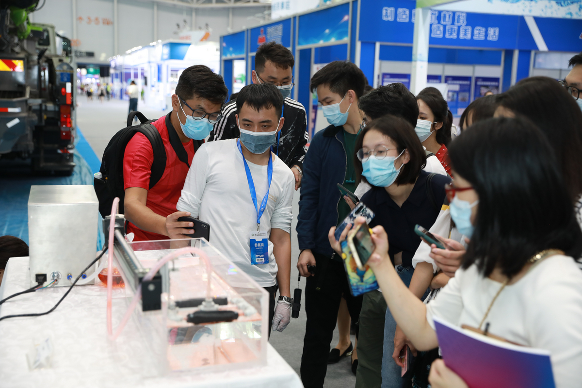 技术人员向记者介绍高效回收水面薄油膜无人艇(船)集成装置。图/佛山日报记者 张弘弢摄