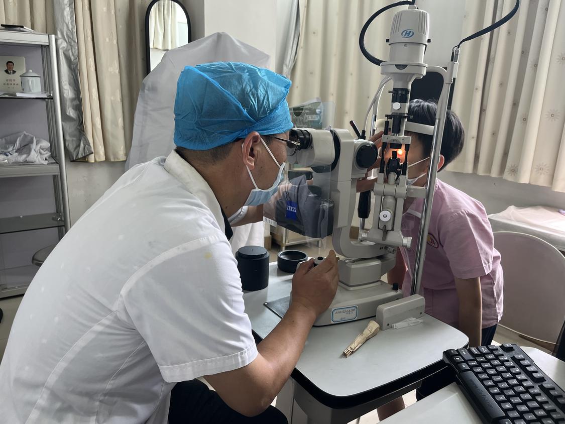 高明区人民医院眼科主任熊义斌正在为一名学生检查眼睛
