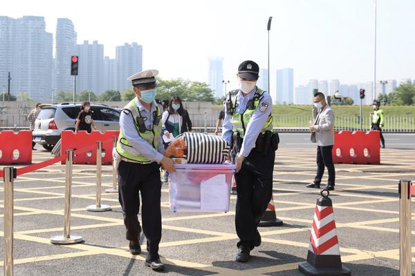 张槎中学校门口,交警帮助学生搬运书籍行李。/佛山日报记者符诗贺摄