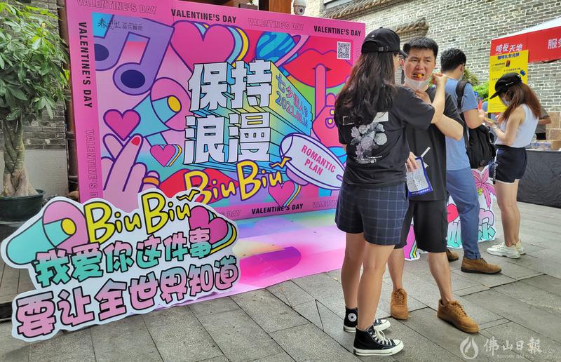8月14日下午,禅城区岭南天地,一位靓女将美食喂给身旁的男伴。他们背后的商家广告牌标注着“保持浪漫”四个大字。/佛山日报记者周春摄