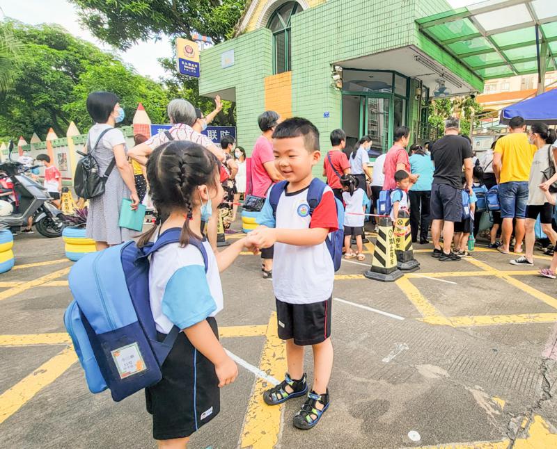 第一天入幼儿园小班的周泽慈在门口遇到邻居妹妹,他们相互握手打招呼。/佛山日报记者周春摄