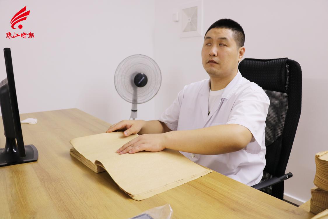 杨震正在阅读盲文医书。.JPG