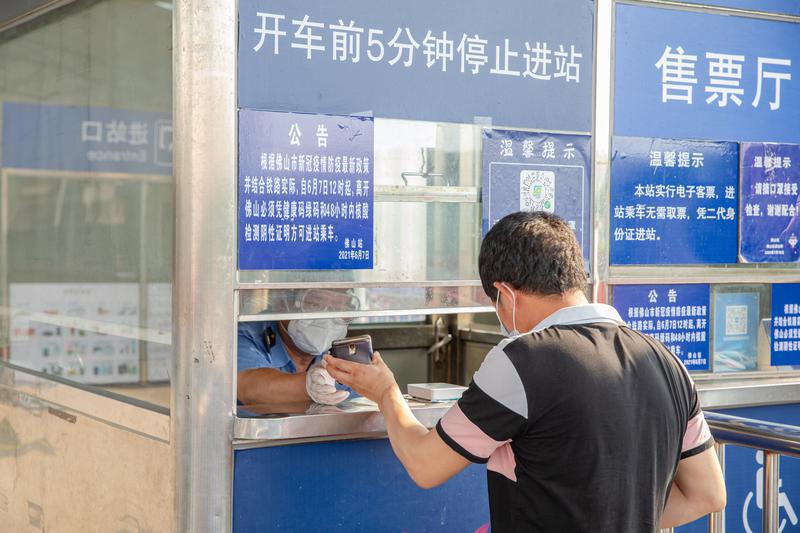 从佛山火车站进站的乘客向工作人员展示48小时内核酸检测阴性的二维码。佛山日报记者周春摄