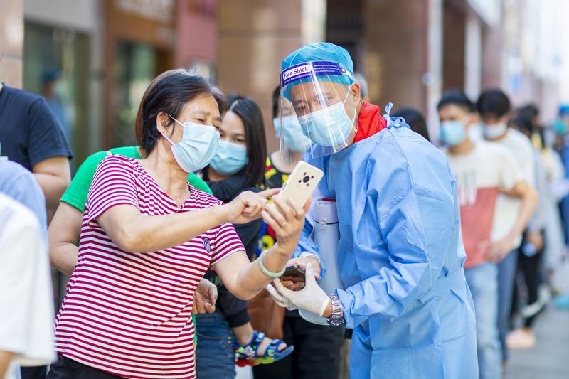 佛燃能源党员志愿者仇日明在普东社区投入疫情防控工作,引导市民有序进行核酸检测。/佛山日报记者符诗贺摄