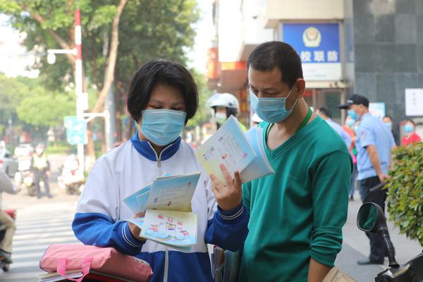 张槎中学校门口,家长和学生一起阅读防疫手册。/佛山日报记者符诗