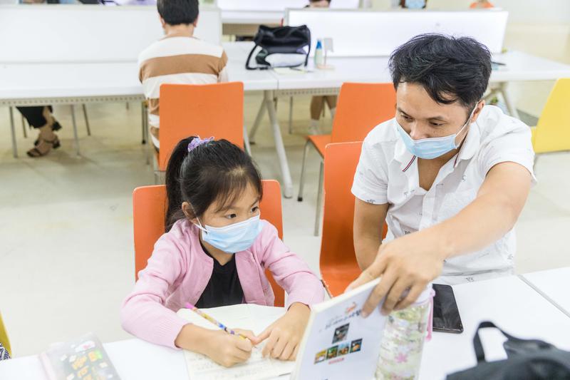 8月29日,佛山市图书馆内,一家长正在与孩子一起复习功课。/佛山日报记者王伟楠摄