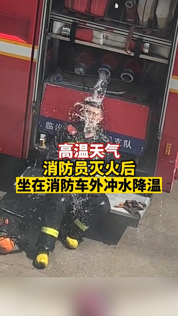 消防员灭火后，坐在消防车外冲水降温