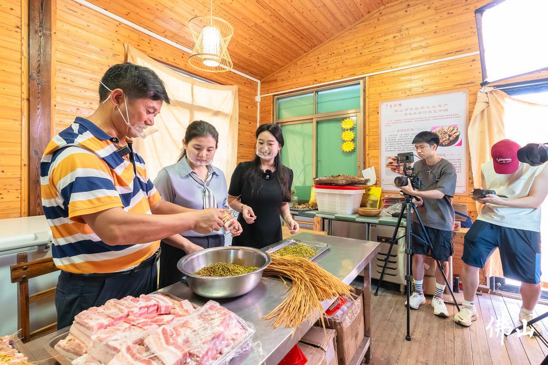 非遗美食研学体验工坊内,记者宋佳雨(左二)与前来研学、拍摄的广东财经大学的大学生一起向非物质文化遗产项目代表性传承人彭叶开(左一)学习禾秆冚珍珠的制作技艺。佛山市新闻传媒中心记者王澍摄.jpg