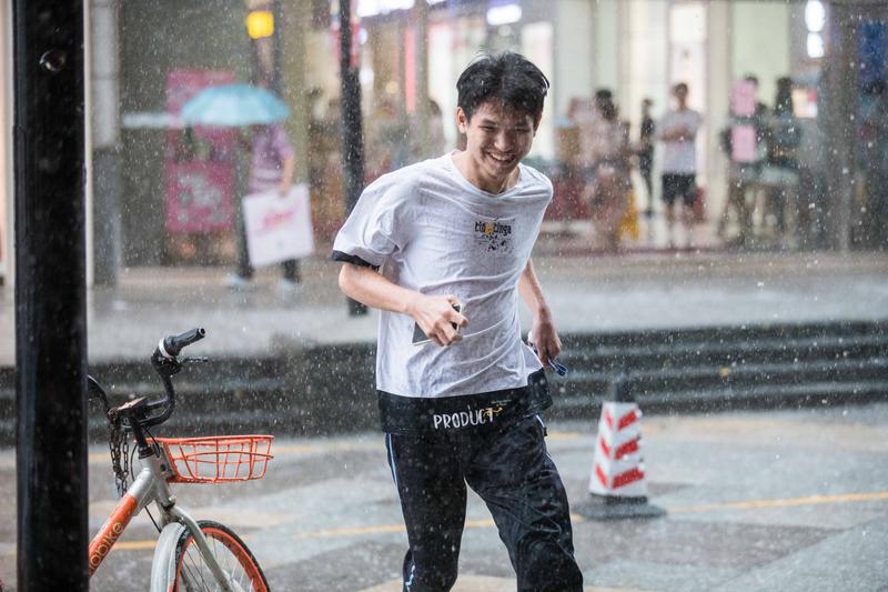 顺德陈村镇顺联广场,一年轻人冒着大雨跑到屋檐下躲雨。/佛山日报记者王伟楠摄