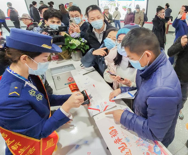 市民在地铁站内将纪念册盖章留念。/佛山日报记者周春摄