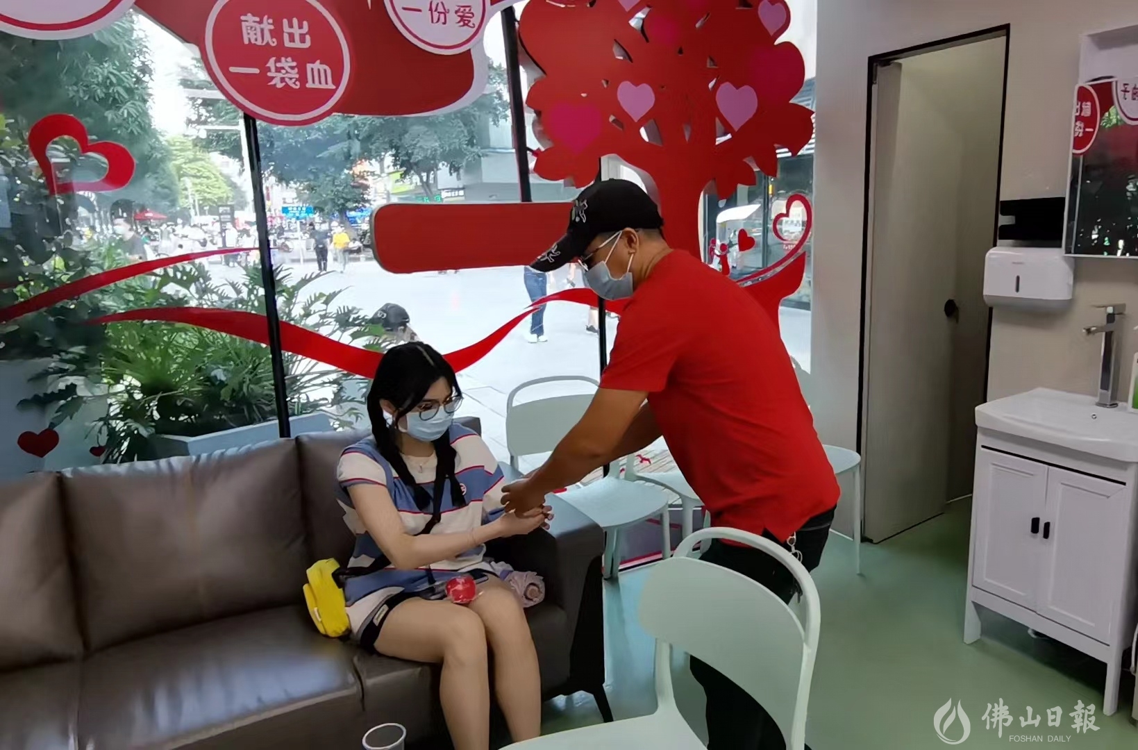 志愿者曾德文向刚完成无偿献血的袁小姐递上温水。(佛山日报记者谈飞洋).jpg