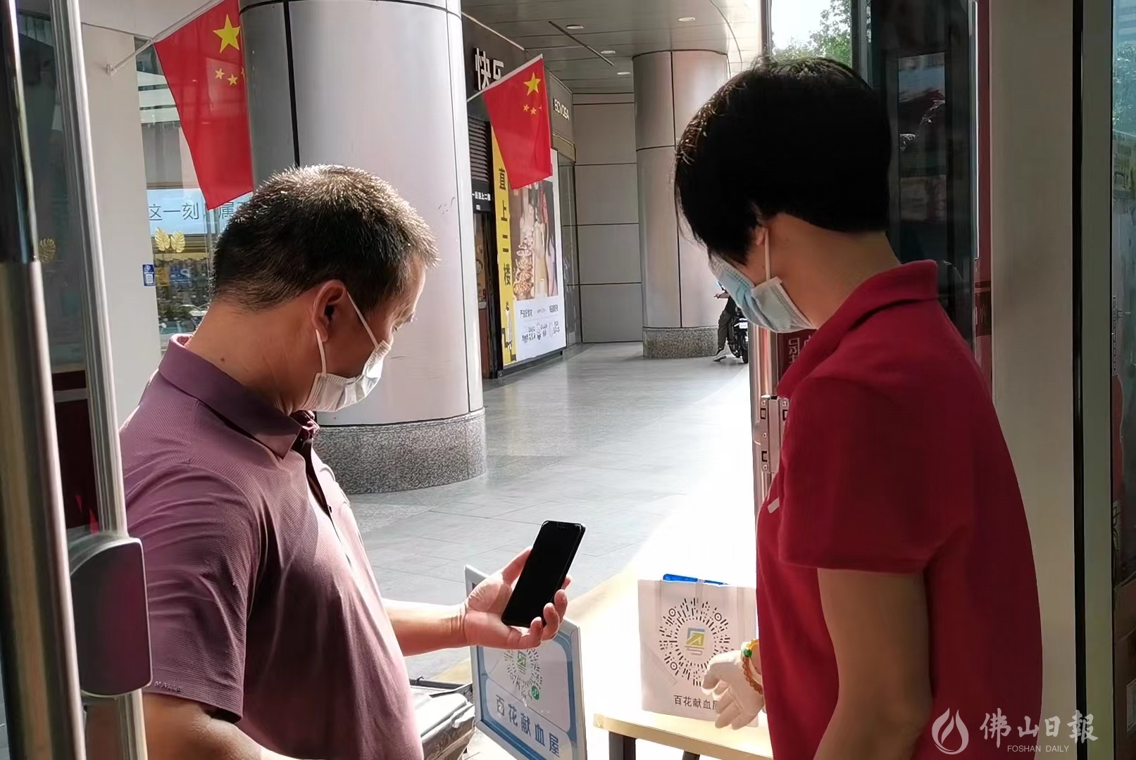 无偿献血志愿者温秋苑指导市民进行场所码打卡。(佛山日报记者谈飞洋).jpg