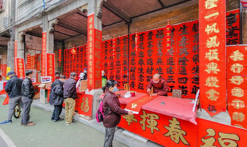 正在书写的华叔已经78岁了，他曾在周边的公正路、锦华路、福禄路等地都写过春联，目前已经写了二十多年了。“不为挣钱，就为一个精神寄托”华叔说。/佛山日报记者周春摄