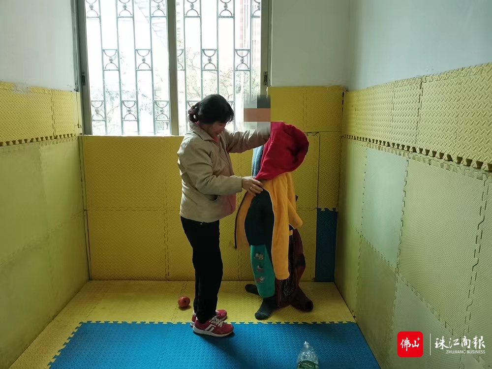 何建英帮儿子穿衣服。受访者供图.jpg