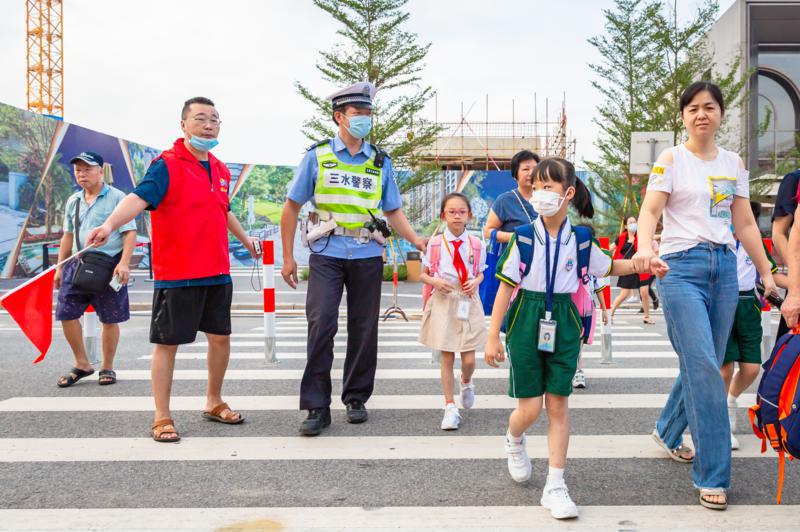 9月1日,开学首日,为了让广大家长顺利送孩子上学,三水全区各个学校均有警家校志愿者维持秩序,三水区云东海街道博文小学门前,警家校志愿者正在与三水公安交警一起在斑马线执勤,护送学生过马路。/佛山日报记者王澍摄